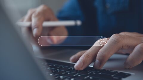 Hände geben etwas auf der Tastatur in die Suche ein