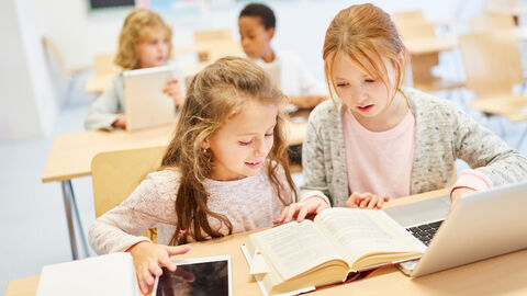 Zwei Mädchen in der Schule über Buch und PC