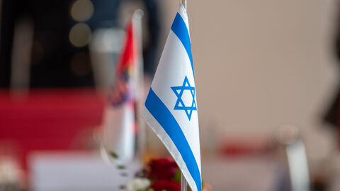 Eine kleine, israelische Flagge steht auf einem Tisch. Im Hintergrund ist ebenfalls die hessische Flagge zu sehen.