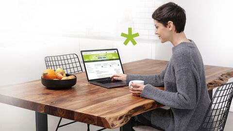 Eine Frau sitzt am Tisch und ruft über ihr Notebook die Seite zur elektronischen Steuererklärung auf.