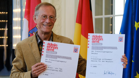 Staatsminister Axel Wintermeyer hält zwei Förderzusagen in der Hand