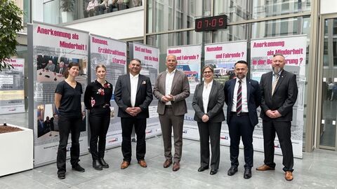 Innenminister Roman Poseck unter anderem mit dem stellvertretenden Geschäftsführer des Landesverbades Hessen Deutscher Sinti und Roma Rinaldo Strauß, der Vizepräsidentin des Polizeipräsidiums Südosthessen und weiteren Bediensteten des Polizeipräsidiums Südosthessen. Sie stehen gemeinsam vor Aufstellern der Ausstellung.