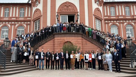 Innenminister Roman Poseck sowie zahlreiche Gäste stehen vor dem Schloss Biebrich Wiesbaden